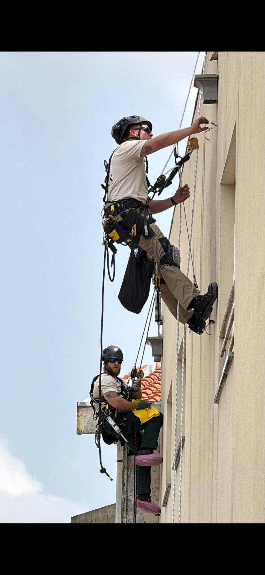 Técnicos da RopeX em acesso por cordas a intervir na fachada de um edifício de quatro pisos em Baltar