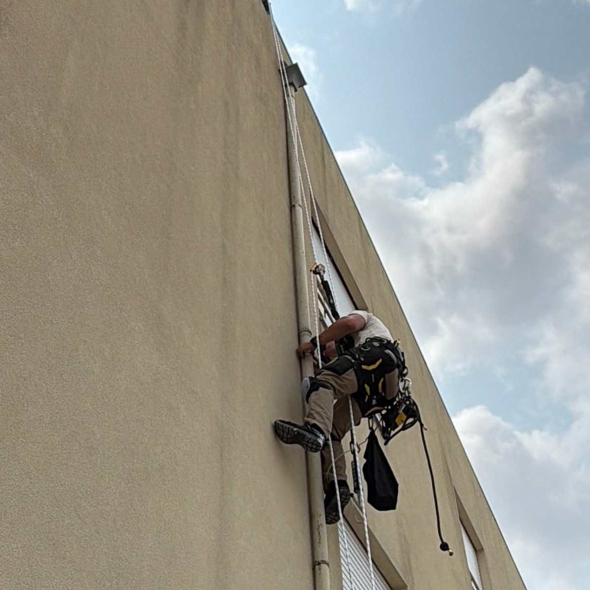 Técnico da RopeX suspenso por cordas na fachada de um edifício