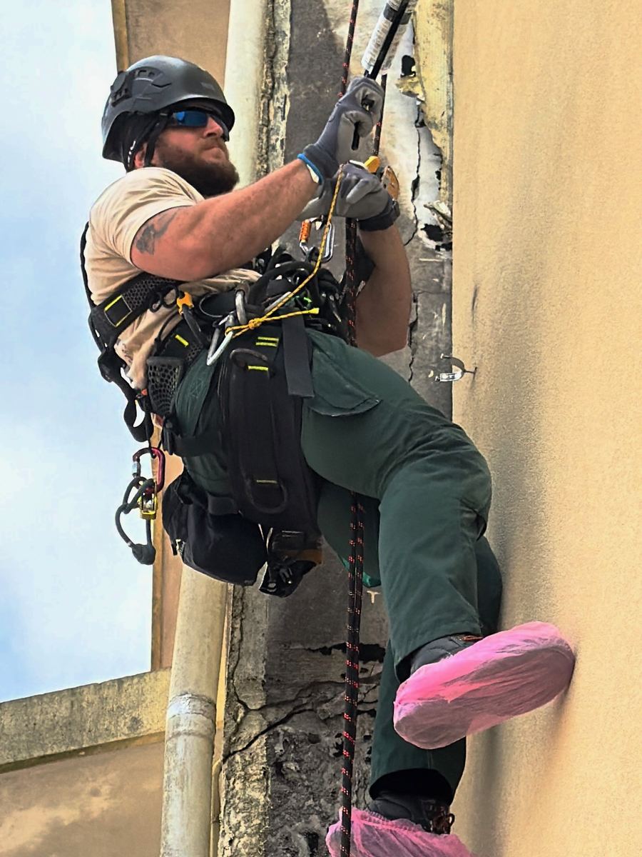 Técnico da RopeX suspenso por cordas numa fachada de edifício